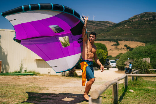 Young shirtless man holding hydrofoil at beach on sunny day