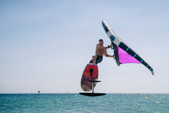 Shirtless young man with hydrofoil over sea on sunny day