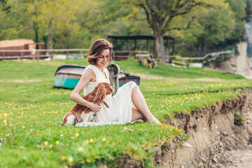Smiling woman sitting with pet dog on grass