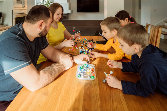 Parents and children with molecular structures on table at home