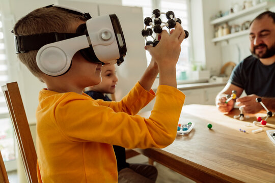 Boy wearing virtual reality goggles examining molecules at home