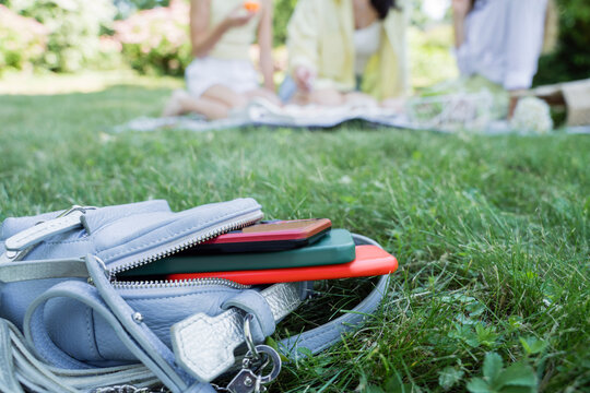 Backpack with mobile phones on grass in park