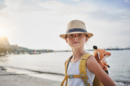 Smiling girl with stuffed toy in bag at beach