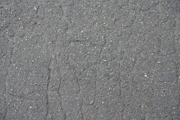 Surface of old wet asphalt with numerous cracks