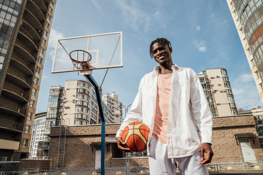 Smiling man young man standing with basketball at sports court