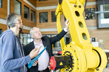 Senior customer getting advise on industrial robot from expert staff