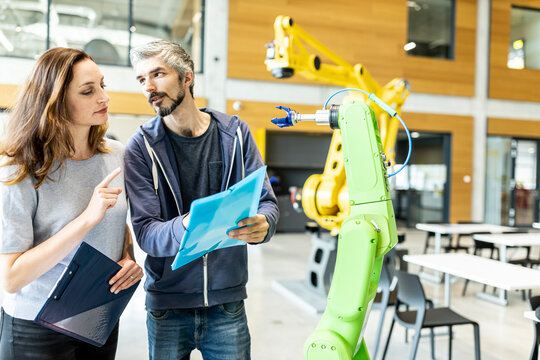 Technicians having meeting in front of industrial robot