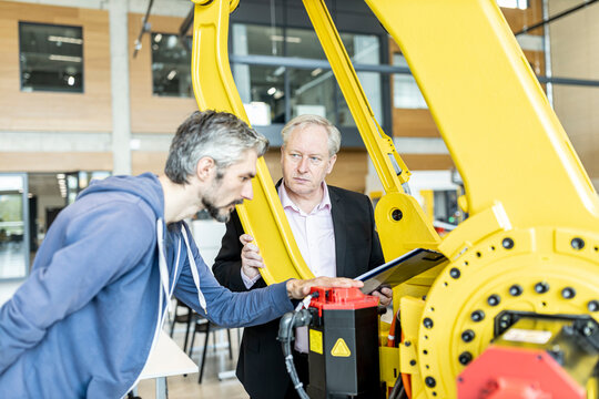 Senior customer getting advise on industrial robot from expert staff