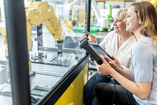 Women in factory using control of industrial robot