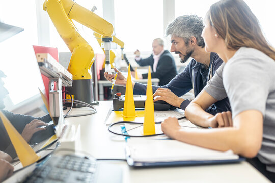 Engineers in factory developing new robot arm