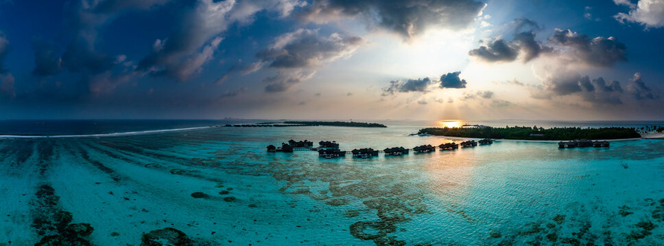 Maldives, North Male Atoll, Lankanfushi, Aerial view of Indian Ocean at sunset with tourist resort bungalows in background