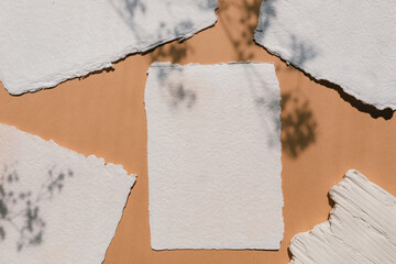 Aesthetic flat lay of handmade paper sheets mockup on terracota shadow background. Wedding...