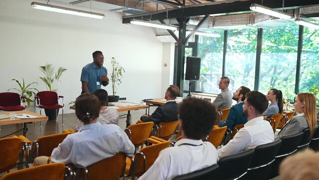 Video of a business conference meeting with an educator speaking to the people in the room. Cinematic footage representation of public speaking concepts and self improvement motivational summits