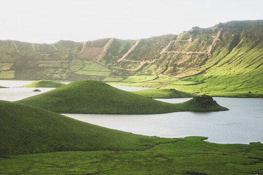 Idyllic view of lake amidst green hills on sunny day