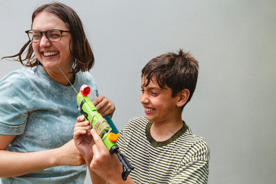 Happy son and mother enjoying playing with water pistol