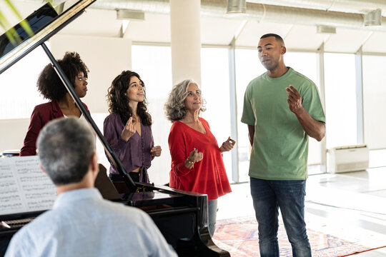 Businessman singing by colleagues snapping fingers in office