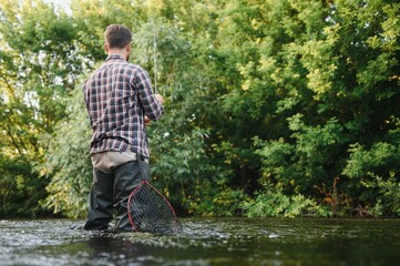 Fishing. Fisherman and trout. Fisherman on wild river. - obrazy, fototapety, plakaty