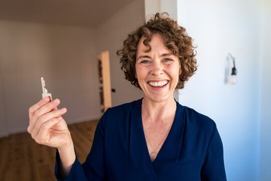 Happy real estate agent with house key at new home
