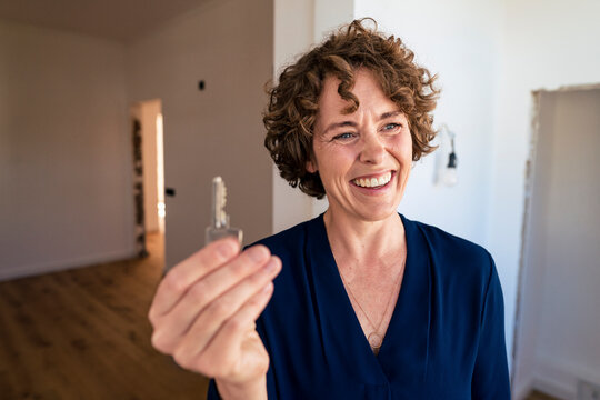 Happy saleswoman showing house key at new home