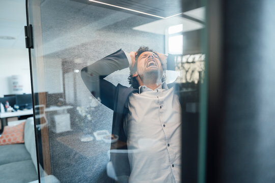 Frustrated businessman screaming in soundproof cabin at office