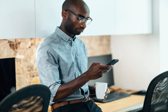 Businessman with coffee mug using mobile phone at workplace