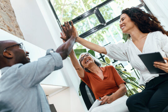Smiling multiracial colleagues giving high-five to each other