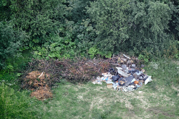 Illegal garbage dump among the trees in the forest. Garbage unlawfully thrown into a clearing in the park