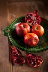 apples and pomegranates on green plate