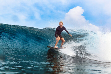 Happy man surfing on sea in front of cloudy sky