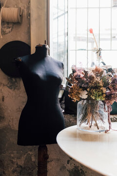 Dressmaker's Mannequin By Flower Vase On Table At Workshop