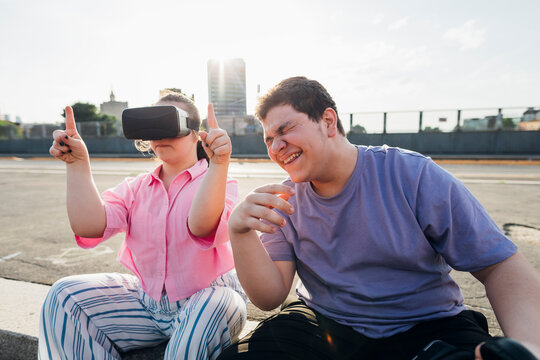 Brother laughing by sister with down syndrome wearing virtual reality simulator