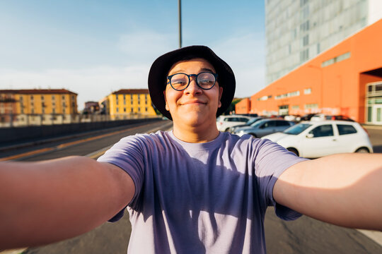 Smiling teenage boy with eyeglasses taking selfie on sunny day