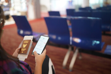Obraz premium Woman waiting for departure at the airport on your vacation hold passport and smartphone while waiting boarding on departure area International Airport