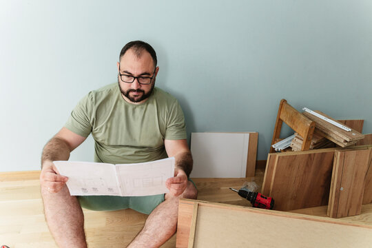 Man reading instruction manual sitting on floor at home