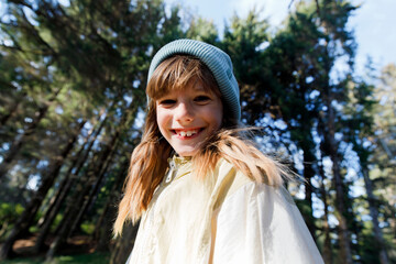 Happy blond girl wearing knit hat on sunny day