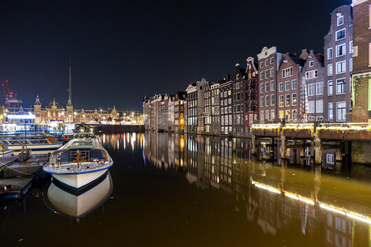 Netherlands, North Holland, Amsterdam, Long exposure of Damrak canal at night with rowhouses in background