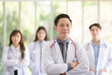 Group of Asian doctors team portrait standing with colleagues in background.