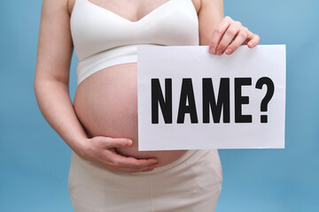 Pregnant woman holding paper with text Name and question mark, blue studio background