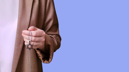Woman teacher holding religious symbol jewish six-pointed star on studio blue background, banner close-up