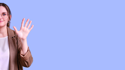 Woman teacher waving hand in greeting gesture on studio blue background, banner copy space
