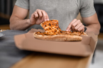 Hands of man sitting at table taking pizza