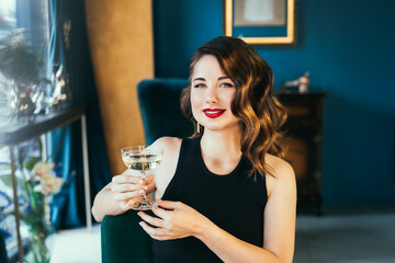 Portrait of posh elegant woman in evening dress with a glass of champagne in the luxury interior. Celebrity, superstar lifestyle. Party, drinks, holidays and celebration concept. Selective focus