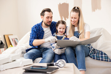 A grown man, together with family, is sitting on the sofa and discussing what color will look best in their children's room. Everyone is happy that they have started the long-dreamed-of renovation.