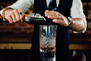 close up bartender adding ice in glass