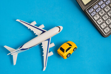 Calculator,model an airplane and car blue background. Concept costs expenses for air travel and...
