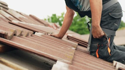 Tired worker placing roof tiles on top or private home, side view