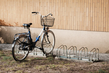 Retro bike with shopping basket is parking on station near yellow wall of store or house