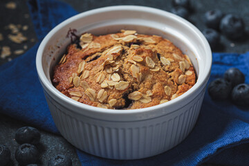 Vegan oatmeal, banana, blueberry mug muffin on blue background. Plant based dessert.