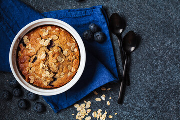 Vegan oatmeal, banana, blueberry mug muffin on blue background. Plant based dessert.