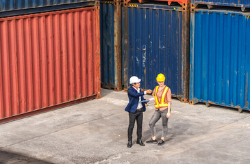 Professional two engineer container cargo foreman in helmets working standing and using walkie talkie checking stock into container for loading.logistic transport and business industry export